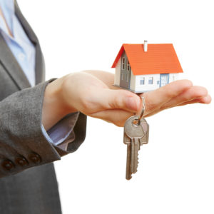 man holding a miniature house and keys